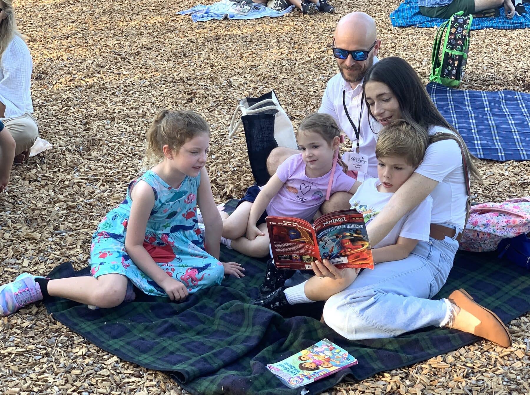 Families reading together outdoors.