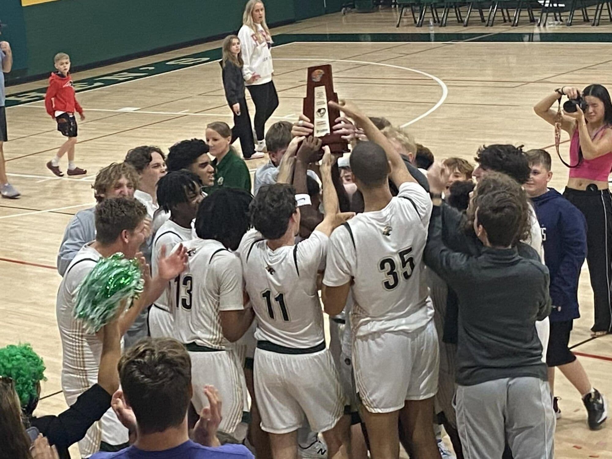 The Saint Stephen's boys basketball team hoists the district championship trophy in 2026.