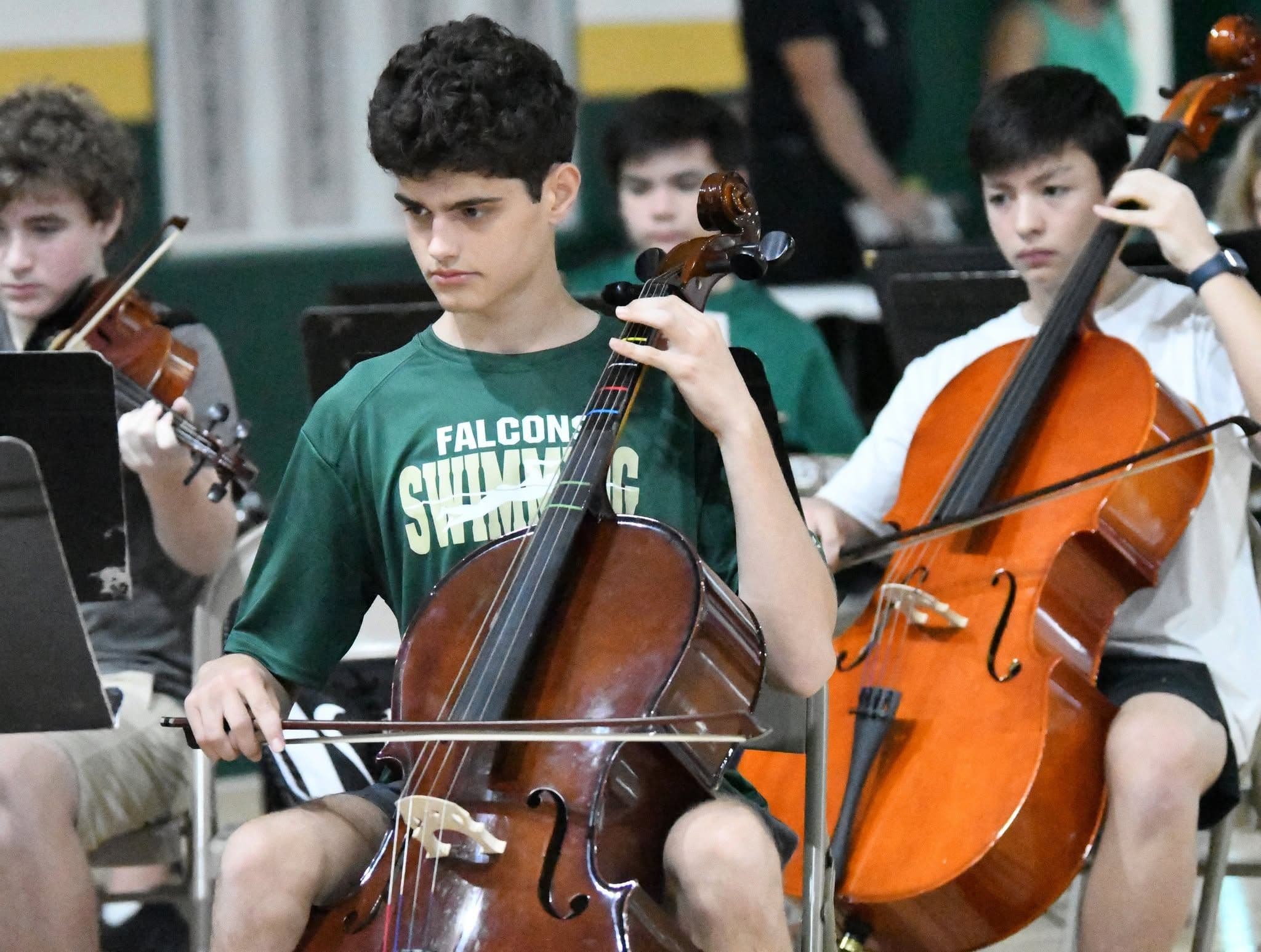 Students play stringed instruments at a recital